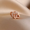 Rose gold heart pendant featuring small clear stones, resting on a beige fabric.