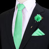 Chaqueta negra con camisa blanca y corbata de seda verde lima brillante, prendido con una flor verde floral