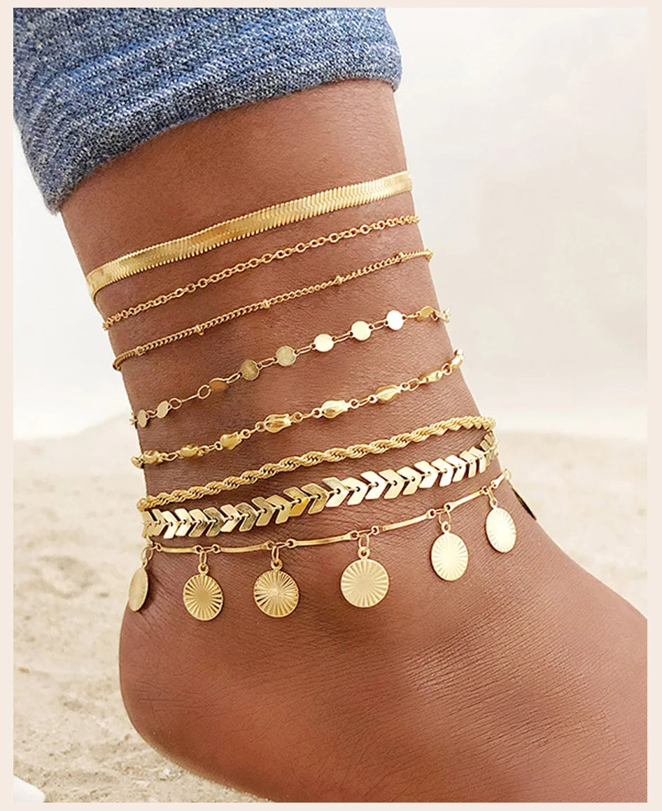 Gold stainless steel snake chain anklets layered on a woman's foot.