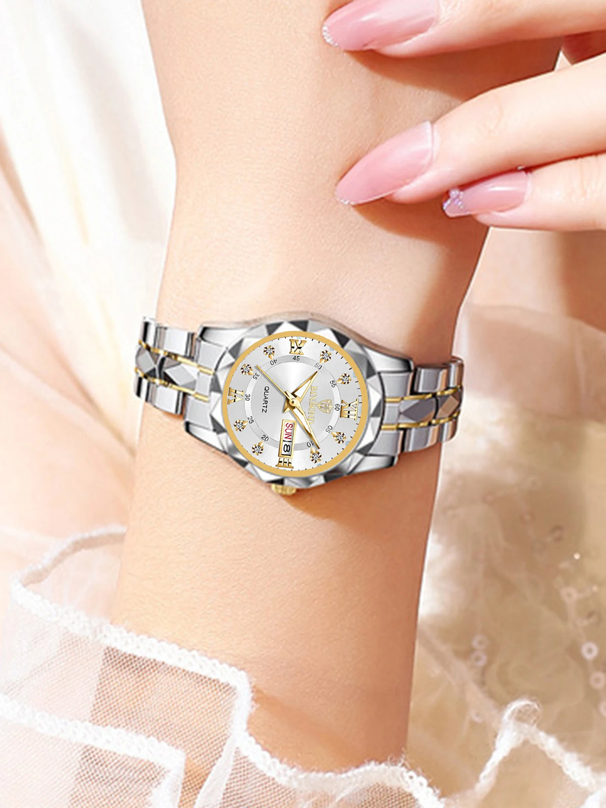 A close-up of a stainless steel couple watch with gold accents on a wrist.