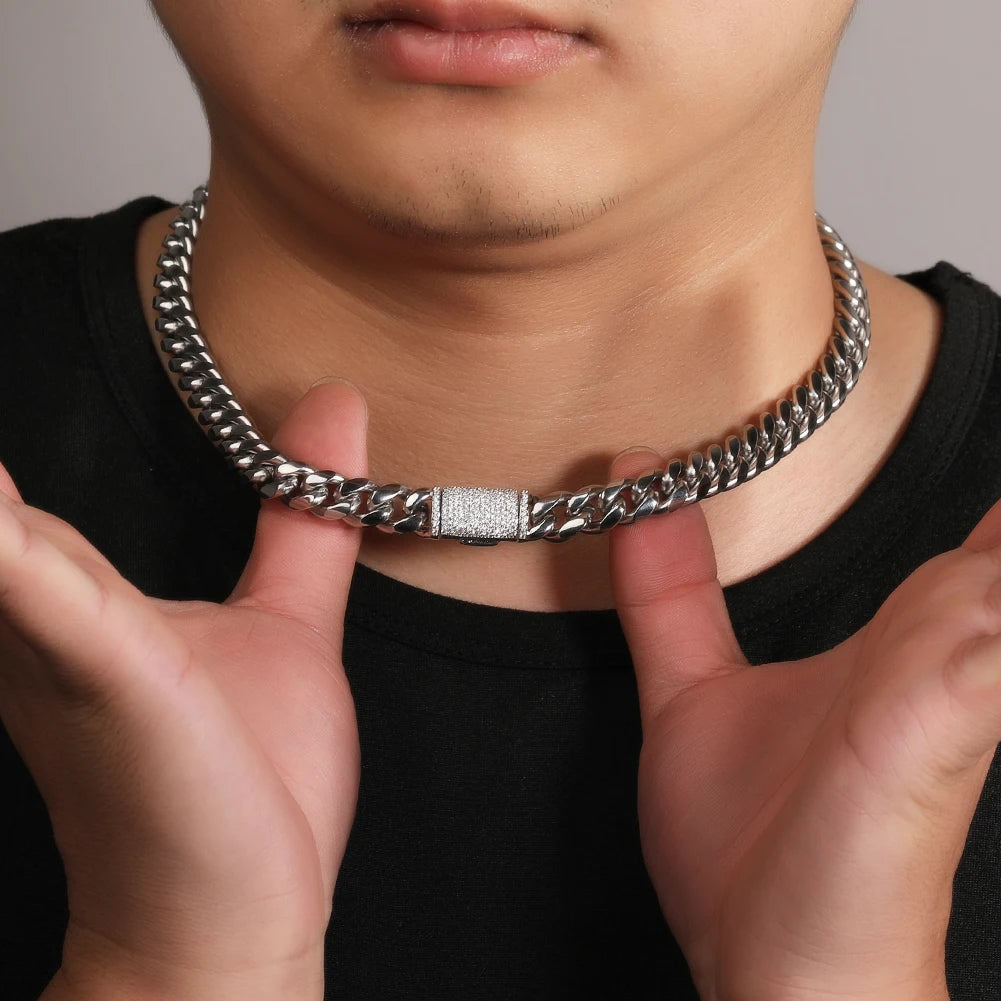 A close-up of a stainless steel Cuban link necklace being held against a person's neck.