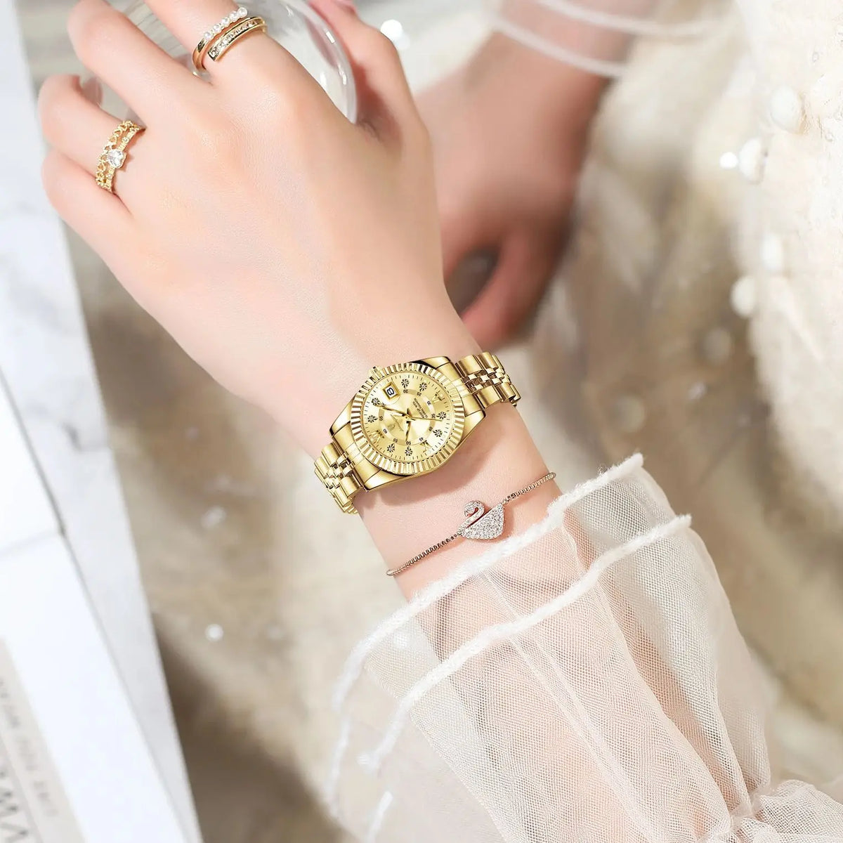 A close-up of a woman's hand wearing an elegant gold stainless steel quartz ladies wristwatch with luminous features.