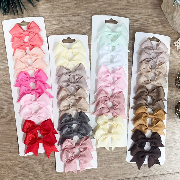 A set of solid color kids bow hair clips in various shades including pink, red, purple, and beige.