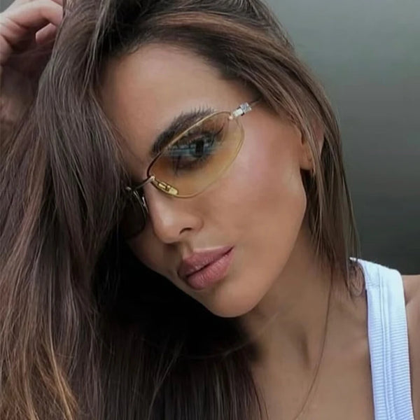 لقطة مقربة لامرأة ترتدي نظارات شمسية بإطار بيضاوي بدون إطار من طراز Y2K وشعر بني طويل.