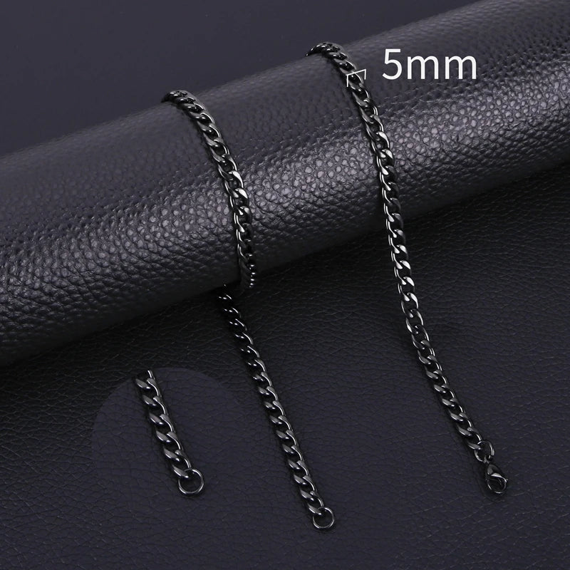 A close-up photo of a black stainless steel Cuban link necklace with a 5mm chain, displayed on a dark leather surface.