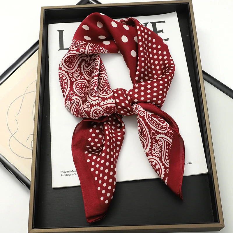 A deep red silk scarf with white polka dots tied in a bow, displayed in a dark frame.