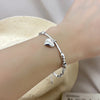 A close-up of a sterling silver double heart charm bracelet worn on a wrist against a light background.