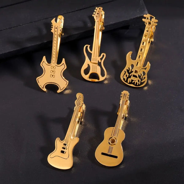 A set of gold-colored titanium tie clips designed for guitars and musical instruments.