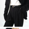 A close-up of a black belt worn over black trousers and a white shirt.