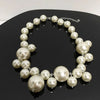 A close-up of an elegant simulated pearl choker necklace displayed on a dark surface.