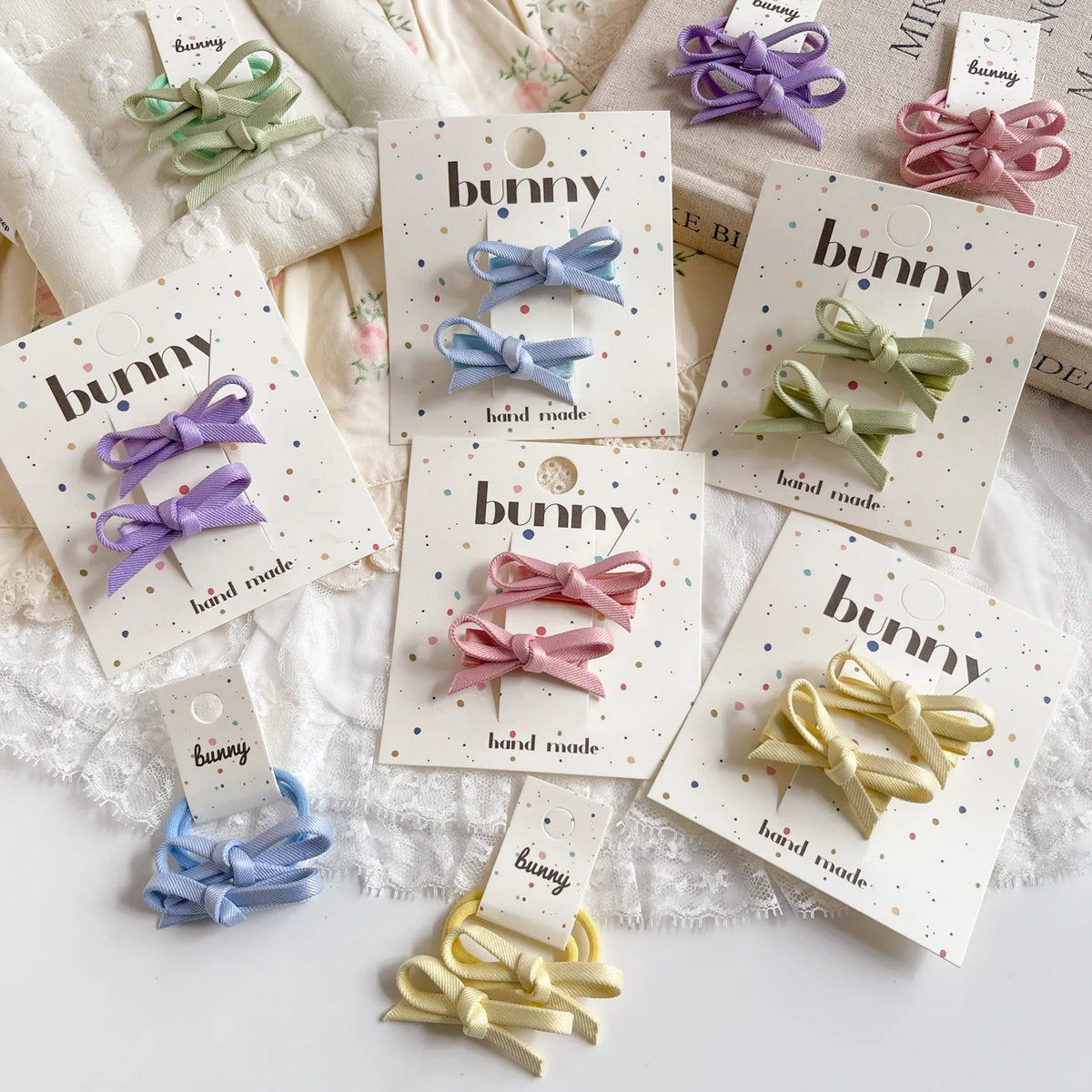 Collection de pinces à cheveux en nœud à la main dans diverses couleurs pastel, y compris bleu, rose et vert, présentées sur 