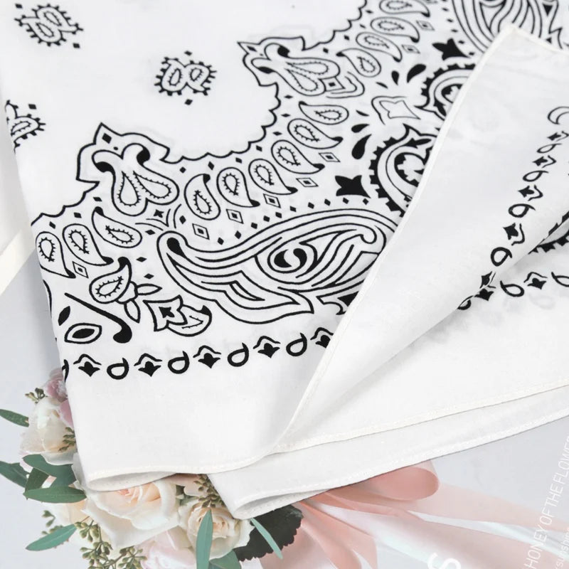 White cotton paisley bandana scarf folded and displayed with floral accents