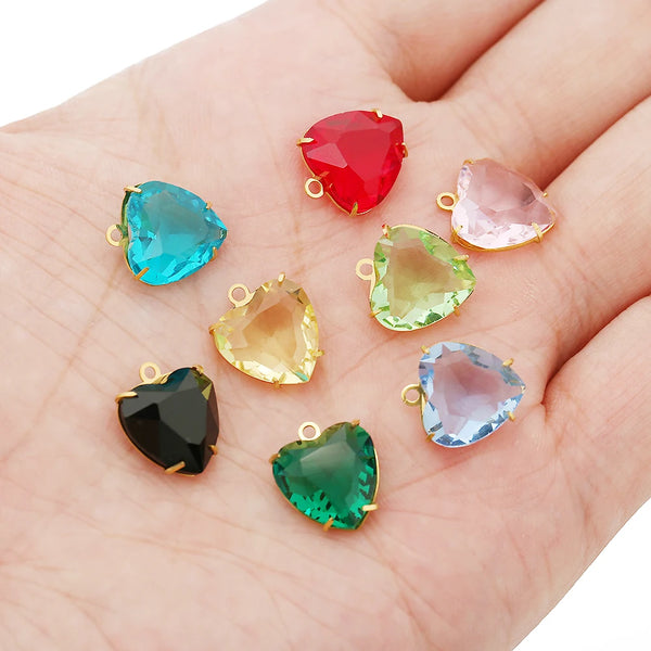Five heart-shaped crystal pendants in various colors including red, blue, pink, yellow, green, and black set against a hand.