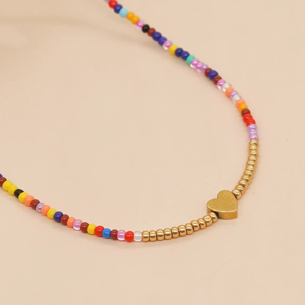 Bunter Perlenhals mit verschiedenfarbenen Perlen und einem kleinen goldenen Herzanhänger