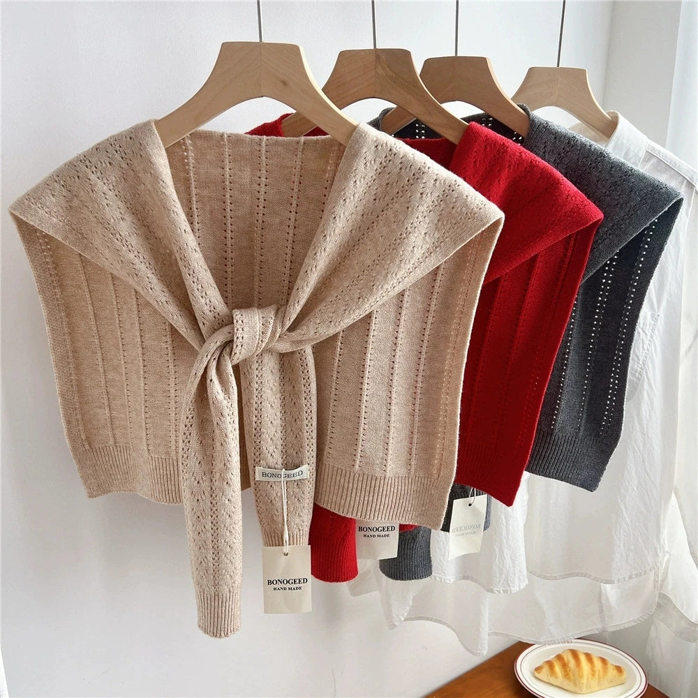 Chal de acrílico tejido beige exhibido en percha de madera.