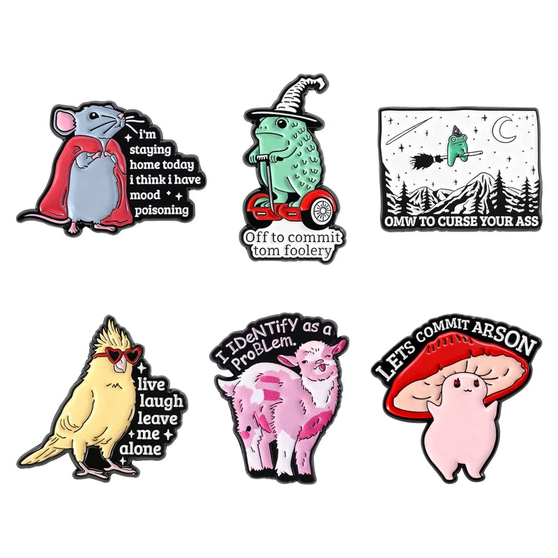 A set of enamel pins featuring whimsical characters including a wizard frog, a pink pig, and a gray mouse.