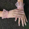 Light pink lace tulle finger gloves worn on a hand against a dark gray fabric background.
