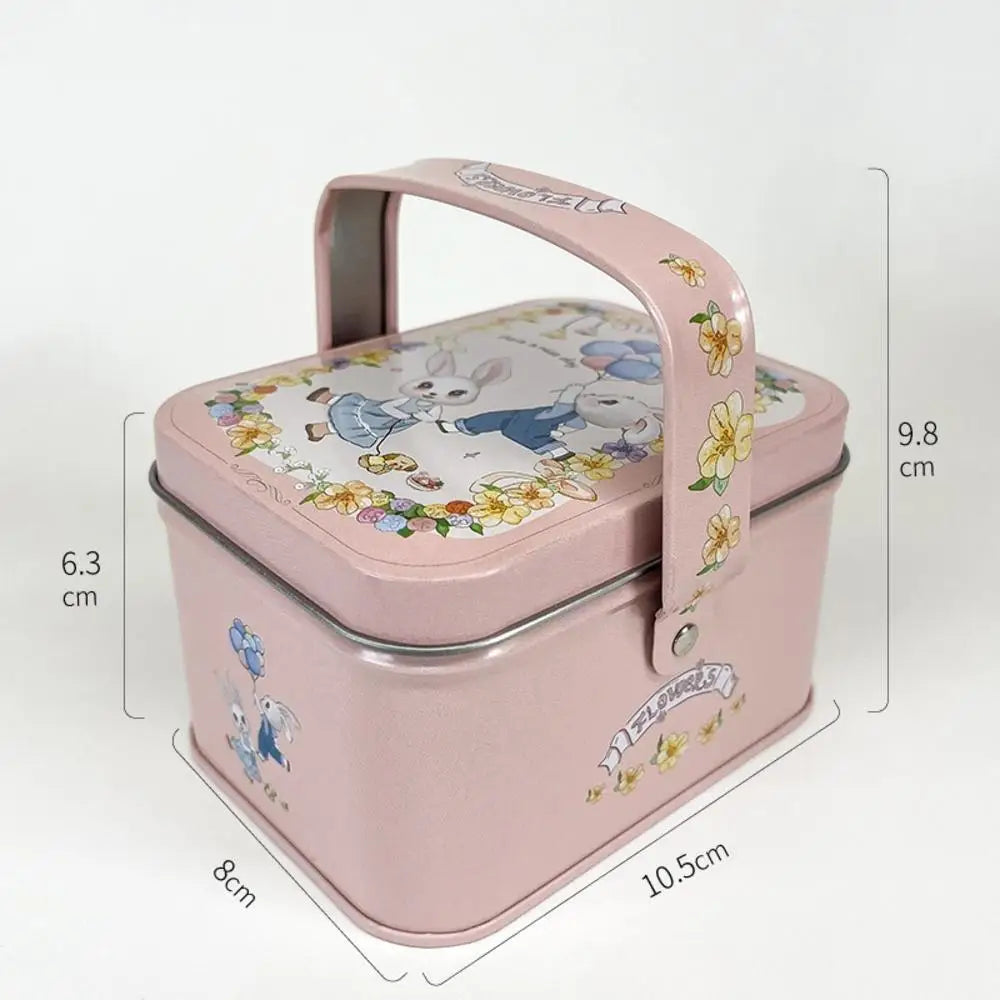 A pink decorative tinplate candy box with a carrying loop featuring a white rabbit design.