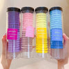 Cuatro recipientes de vidrio llenos de gomas para el cabello con rayas onduladas moradas, rosas, amarillas y azules.
