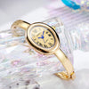 A gold-toned quartz watch with a blue dial and Roman numerals is displayed on a clear, textured glass surface.