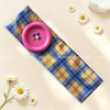 A pink vintage polka dot button headband laid on a light background with white daisies.
