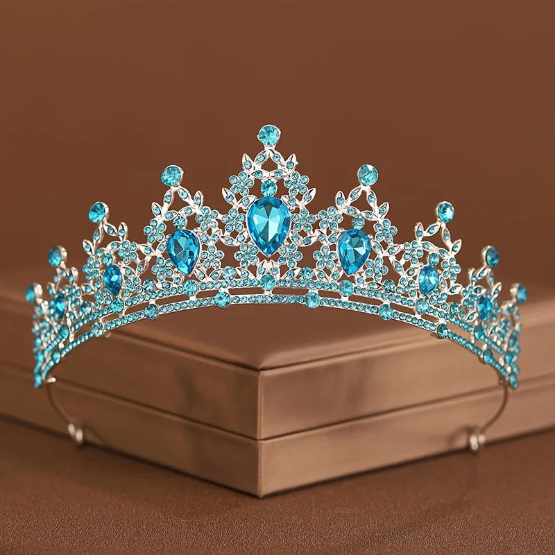 Diadema de tiara de cristal azul con piedras brillantes sobre una caja marrón.