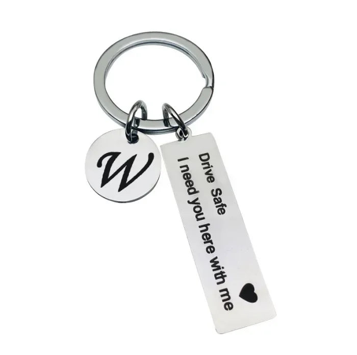Silver keychain with a circular initial W charm and a tag that reads I need you here with me