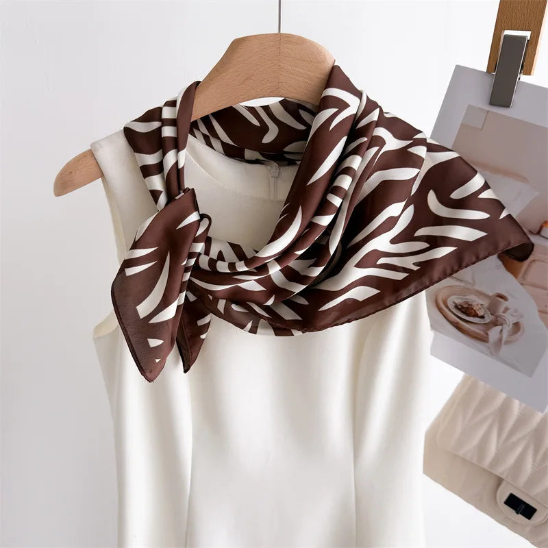 A brown and white zebra print silk scarf draped around a white top.