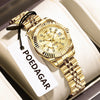 A gold-toned ladies wristwatch with a metal bracelet is displayed on a white card.