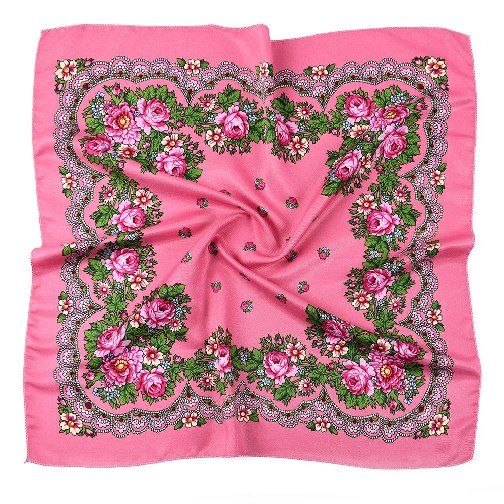 A pink silk scarf featuring a detailed floral print with pink and green roses and foliage.