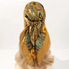 A luxurious satin silk scarf in gold and olive tones tied around a blonde wig.