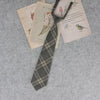 A stack of vintage-style paper and a plaid necktie are displayed on a gray background.