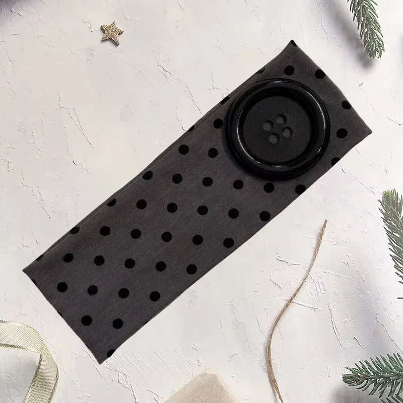 Black stretch hairband with a circular grip and small dots on a white background.