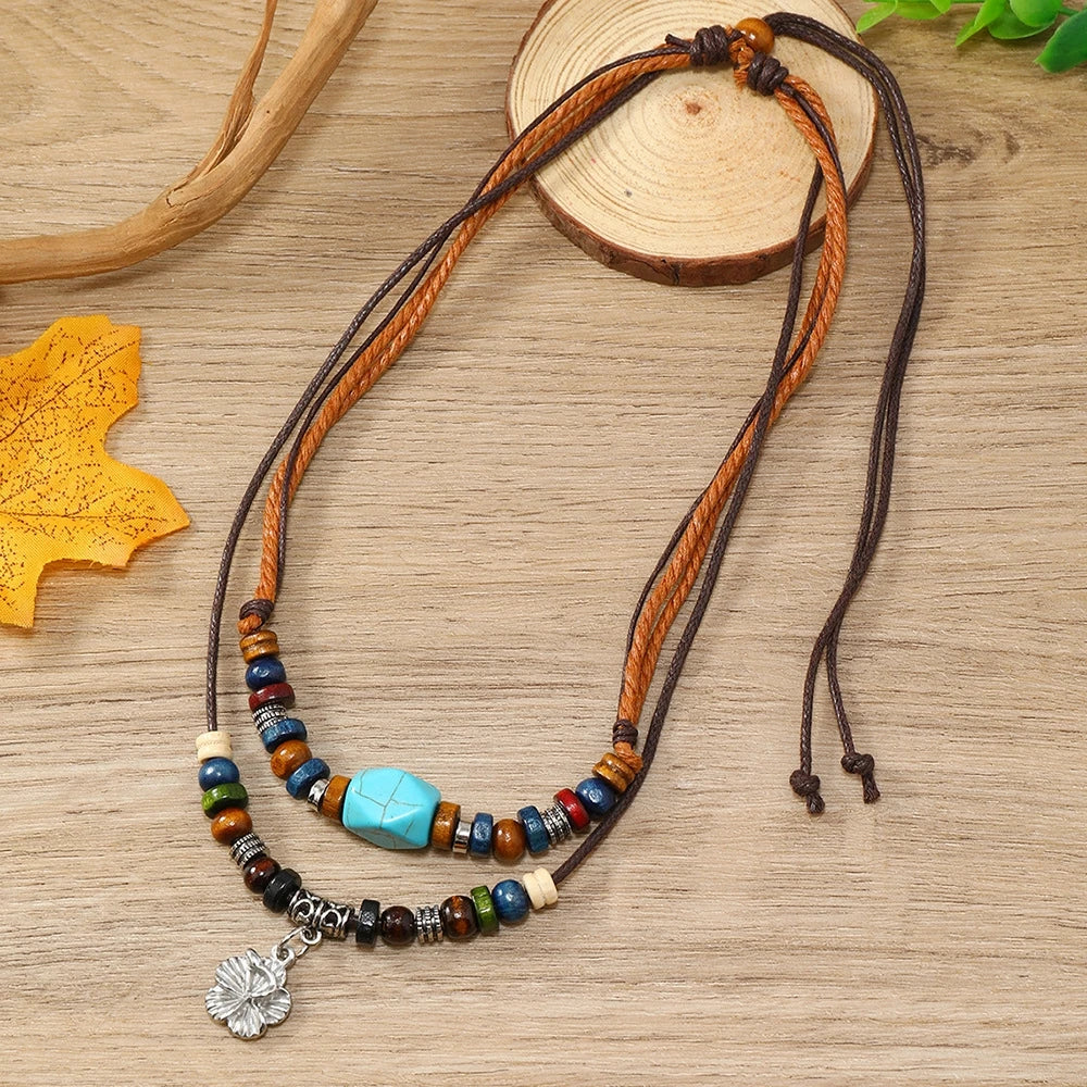 A set of boho vintage wood bead necklaces featuring brown and blue beads with a silver charm on a light wooden surface.