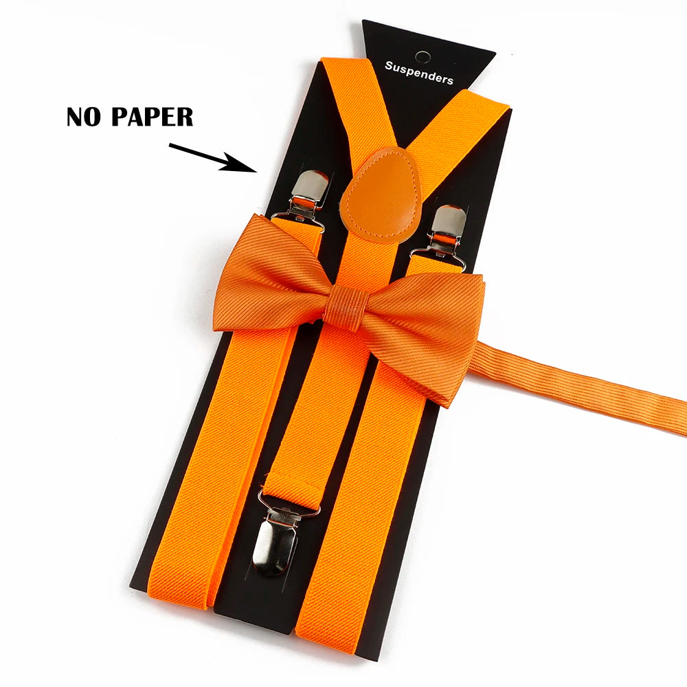 Orange suspenders with bow ties on a black background, showing no paper.