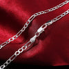 A set of sterling silver charm necklace and bracelet displayed on a red velvet fabric.