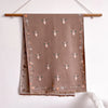 A beige pashmina shawl with a floral print featuring small bee motifs and dried foliage, hanging on a wooden hanger.