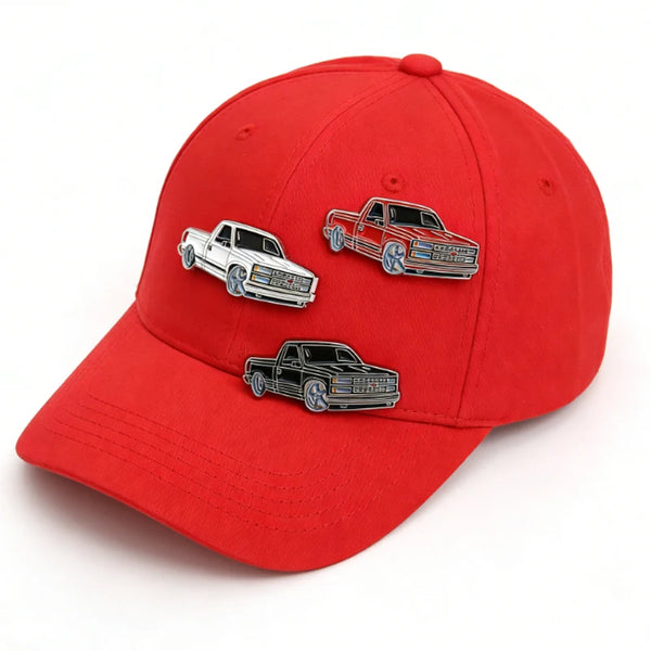 Red baseball cap featuring three silver metal clip pins of classic American cars