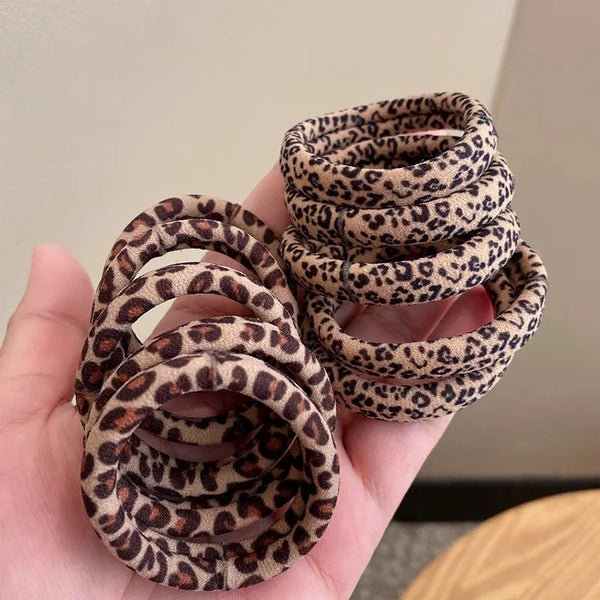 A stack of leopard print elastic hair ties for ponytails held in a hand.