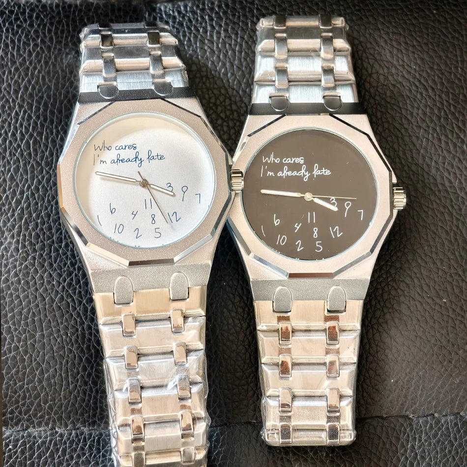 A pair of stainless steel octagonal watches with a slogan dial resting on a dark surface.