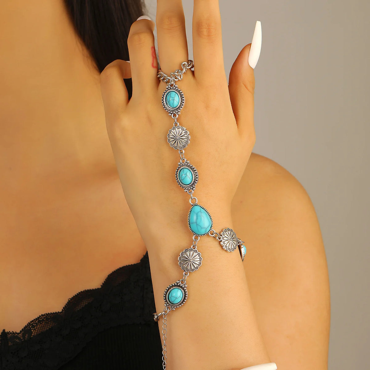 A hand is wearing a silver beaded bracelet set featuring turquoise and silver beads.