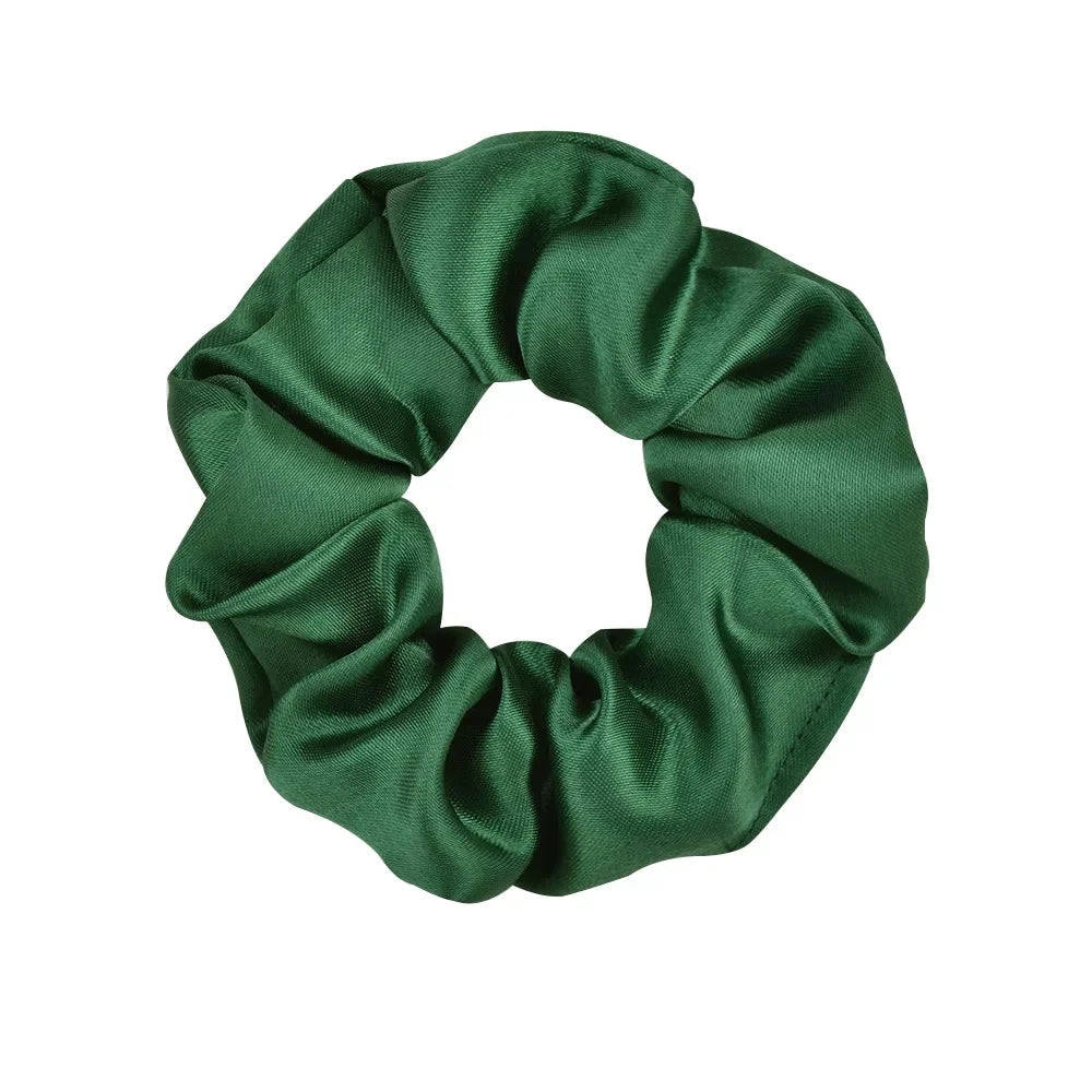 A dark emerald green satin scrunchie tied in a gathered fabric loop.