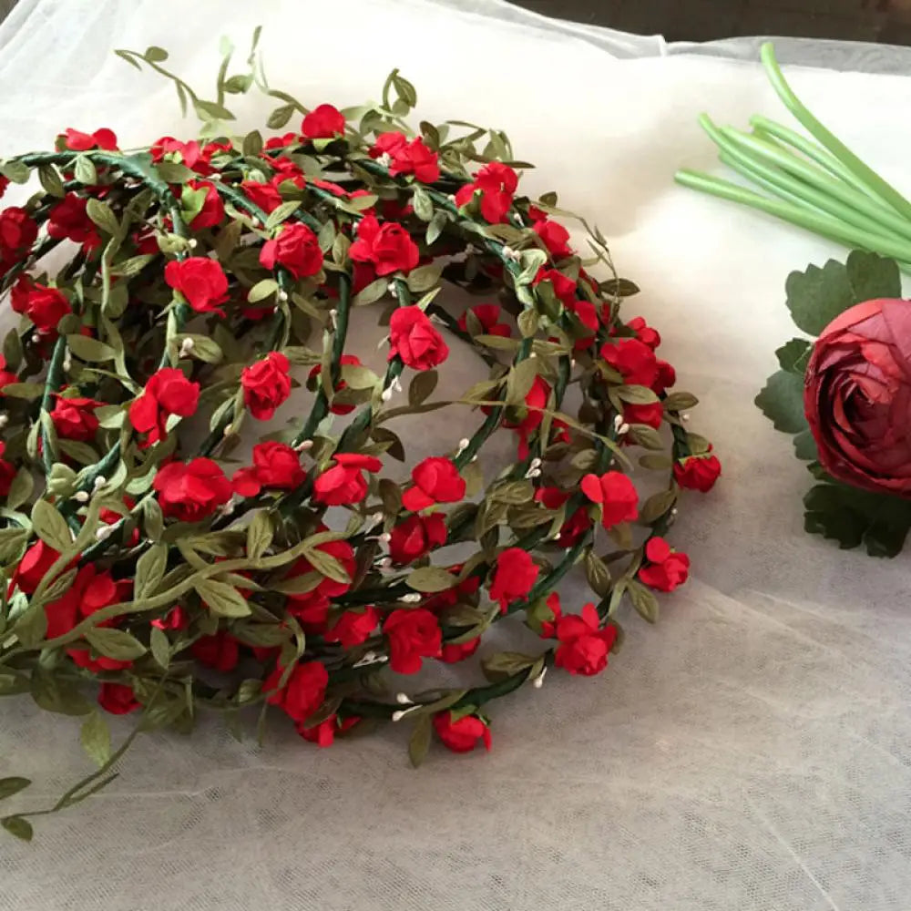 A wreath of red roses and green leaves used as a bohemian flower headband for women.