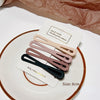 A set of vintage frosted geometry hair clips in various muted pink and brown tones displayed on a white plate.
