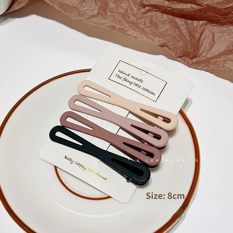 A set of vintage frosted geometry hair clips in various muted pink and brown tones displayed on a white plate.
