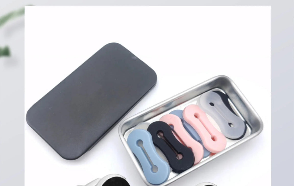 Una bandeja plateada contiene varias hebillas ajustables para extensiones de mangas de camisa en varios colores como negro, r