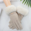 A pair of beige plush wrist gloves with white faux fur cuffs resting on a white surface.