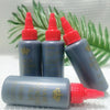 A bottle of professional hair bonding glue in a dark gray plastic container with a red cap, set against green foliage.