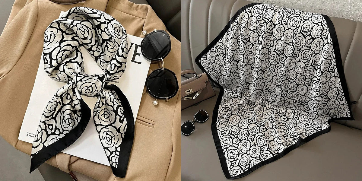 A black and white floral print silk scarf draped on a beige blazer and displayed next to a folded scarf.