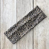 Diadema deportiva impermeable con estampado de leopardo negro y marrón sobre una superficie de madera clara.